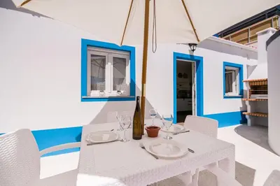 a white table with wine glasses and an umbrella at LovelyStay - Sweet Escape II - Backyard in Quarteira