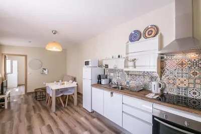 a kitchen with white cabinets and a table at LovelyStay - Sweet Escape II - Backyard in Quarteira