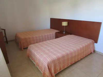 two beds in a hotel room with a plaid blanket at Apartamento - 2 a 4 Pessoas- Piscina in Olhos de Água