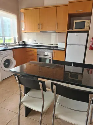 a kitchen with a table and two chairs in it at Apartamento - 2 a 4 Pessoas- Piscina in Olhos de Água