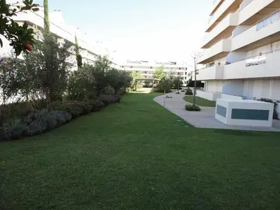 a grassy yard next to a building with a building at Marina Vilamoura Aquamar 203 By Vilamoura Sun in Quarteira