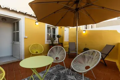 a patio with a table and chairs and an umbrella at Faro Guest House in Faro