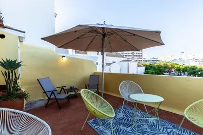 a patio with tables and chairs and an umbrella at Faro Guest House in Faro