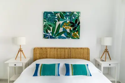 a bedroom with a bed with two lamps and a painting on the wall at Faro Guest House in Faro