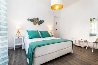 a white bedroom with a bed with green pillows at Faro Guest House in Faro