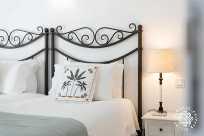 a white bedroom with a bed with blue shoes on it at Casa Julia - Dunas Douradas in Faro