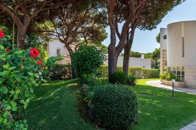 a yard with bushes and trees and a building at Luxury Villa 6 bedrooms with private pool in Vilamoura