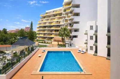 an apartment with a swimming pool in front of a building at Stylish Center Apartment Vilamoura in Vilamoura