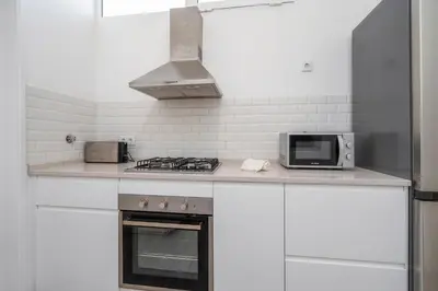 a white kitchen with a stove and a microwave at Sundance Beach House in Faro
