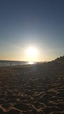 a beach with people walking on the sand and the ocean at Sundance Beach House in Faro