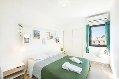 a white bedroom with a green bed and a window at #006 Foxy D by Home Holidays in Albufeira