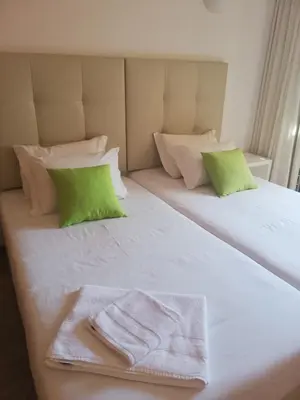 a white bed with green pillows and towels on it at Villa V2 X in Albufeira