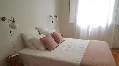 a white bed with two pink pillows on it at Casa aOrta Downtown in Faro