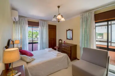 a bedroom with a bed and a chair and a window at Apartamento São Pedro do Mar in Quarteira