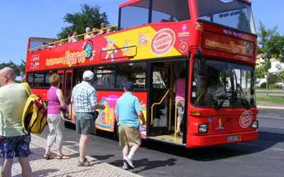 a red double decker bus with people getting on at Love Albufeira - Center, walk to the beach, Old Town, Oura Strip, top location in Albufeira