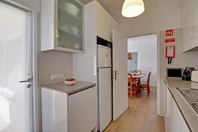 a kitchen with a white refrigerator and a table at Vilamoura Golf Villa 1 With Pool by Homing in Vilamoura