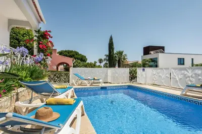 a swimming pool with chairs and a house at Charming Villa With Private Pool in Vibrant Vilamoura, Free AC and Wifi in Quarteira