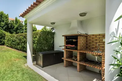 a white house with a courtyard and a yard at Charming Villa With Private Pool in Vibrant Vilamoura, Free AC and Wifi in Quarteira