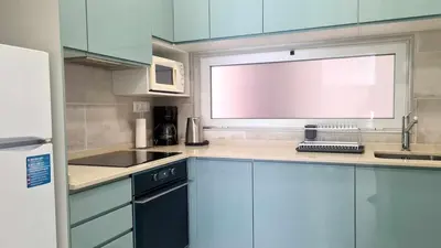 a small kitchen with blue cabinets and a window at Albufeira, with terrace, see views, 5 min to beach (21) in Albufeira