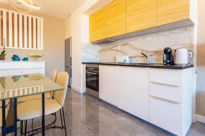 a kitchen with white cabinets and a table with chairs at Marina View Apartment By VilamouraSun in Vilamoura