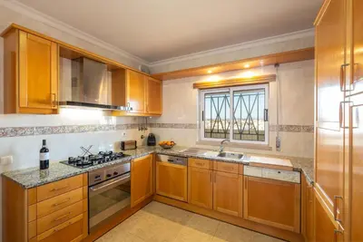 a kitchen with wooden cabinets and a sink and a window at VR Galé Mar in Albufeira