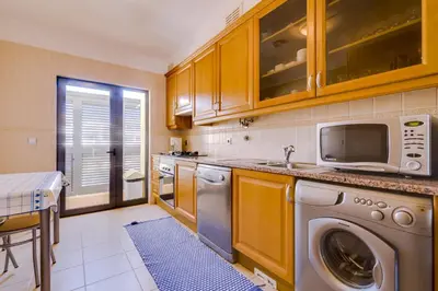 a kitchen with a washing machine and a microwave at Paraísos do Pinhal - 2 Bedrooms - Vilamoura in Vilamoura
