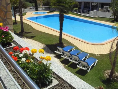 a swimming pool with two lounge chairs and flowers at Apartamentos Pomba Branca in Olhos de Água