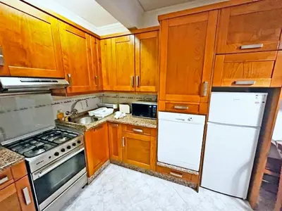 a kitchen with wooden cabinets and white appliances at Quarteira Beach Holidays in Quarteira