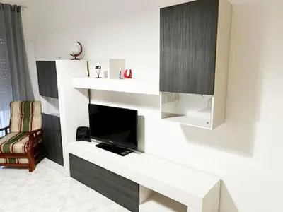 a living room with a tv and a white shelf at Quarteira Beach Holidays in Quarteira