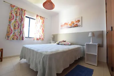 a bedroom with a bed with a blue blanket at Apartamentos Carruna in Albufeira
