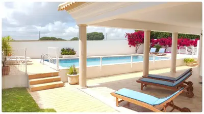 a porch with a chair and a swimming pool at Casa do Mar by Laranjal Rentals in Albufeira
