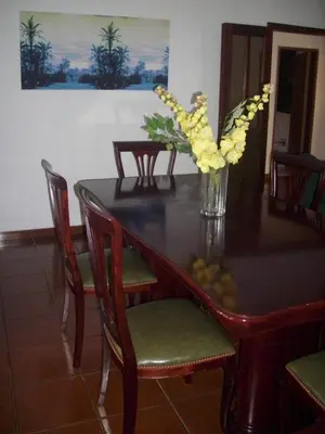 a dining room table with a vase of yellow flowers at Vila Olímpica in Albufeira