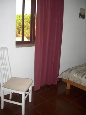 a room with a chair and a window with purple curtains at Vila Olímpica in Albufeira