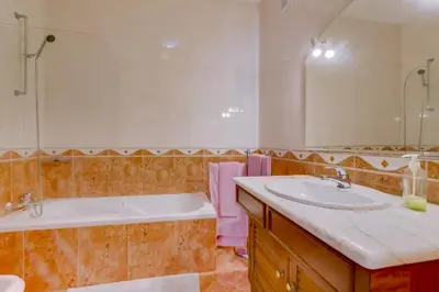 a bathroom with a tub and a sink and a tub and a mirror at Vila Caracas - V3 - Vilamoura in Vilamoura