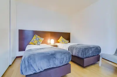 a hotel room with two beds and a chair at Sunset Bacara - Near Vilamoura Marina in Vilamoura