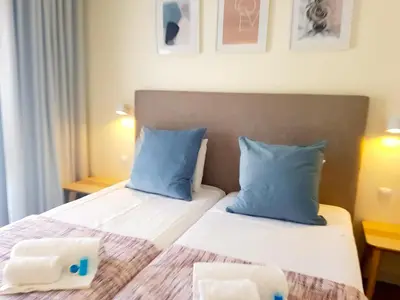 a bedroom with two beds with blue pillows at Ténis Golf Mar CD 14 - Clever Details in Vilamoura