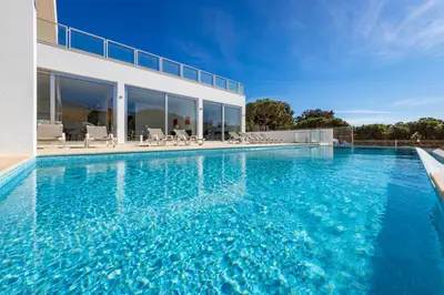 a swimming pool with blue water in front of a house at Villa Ocean Pine in Albufeira