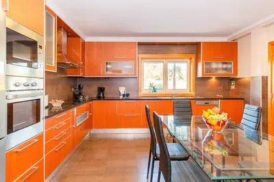 a kitchen with orange cabinets and a glass table at Villa California by Algarve Vacation in Albufeira