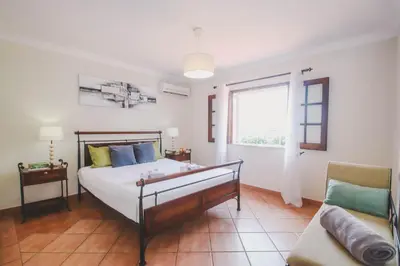 a bedroom with a bed and a couch and a window at Villa Honolulu by Algarve Vacation in Albufeira