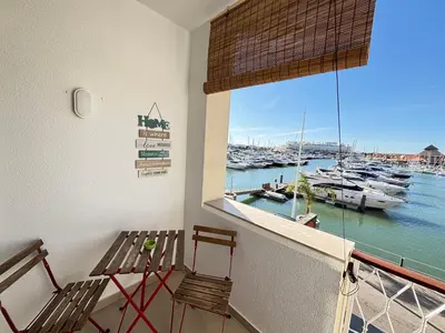 a balcony with two chairs and a window with boats in the water at The Marina Plaza Vilamoura in Vilamoura