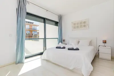 a white bedroom with a bed and a large window at Cavalo Preto Luxury Beach Apartment by Golden Zenith in Quarteira