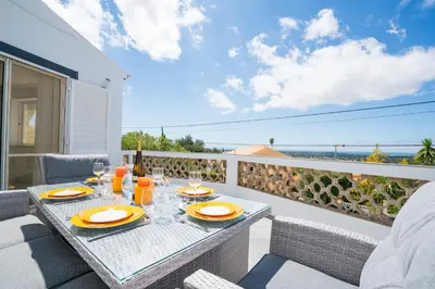 a table on a balcony with a view of the ocean at Casa Laranja Three bedroom Villa in Loulé