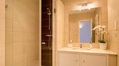 a bathroom with a sink and a shower with a mirror at Sienna in Vale do Lobo