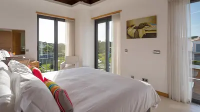a bedroom with a bed with white sheets and windows at Emily in Vale do Lobo