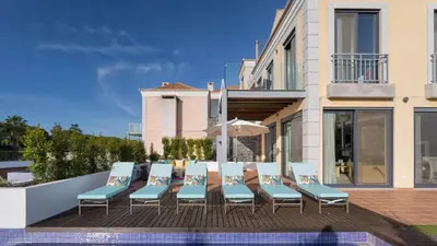 a group of chairs sitting on a deck next to a building at Emily in Vale do Lobo