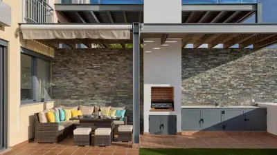 a patio with a couch and chairs and a grill at Emily in Vale do Lobo
