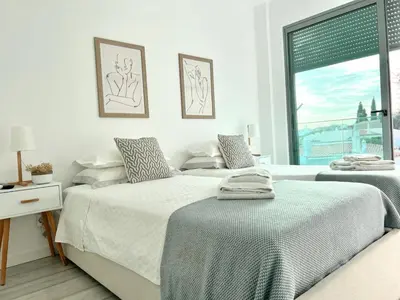 two beds in a white bedroom with a window at Vila Meluna in Albufeira