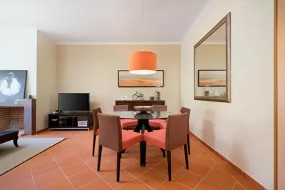 a dining room with a table and chairs and a tv at AL - Apartamentos Vila Sol F5 Bloco 3 in Quarteira