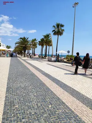 a cobblestone street with palm trees on the beach at Alsol C 5360 in Quarteira