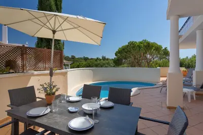 a patio with a table and an umbrella and a pool at Aleisha in Vale do Lobo
